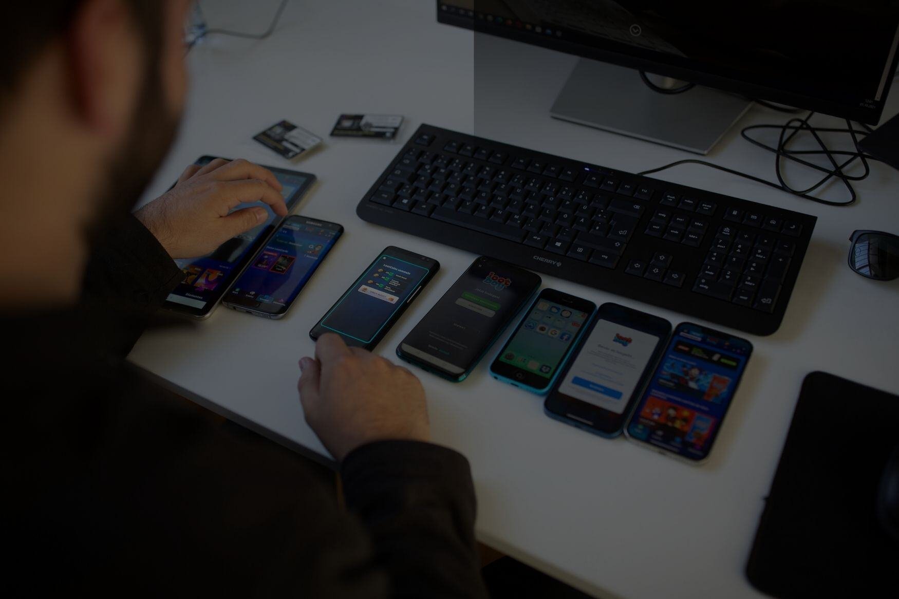 Verschiedene Smartphones liegen auf dem Tisch und werden von einem Tester zum Testing genutzt