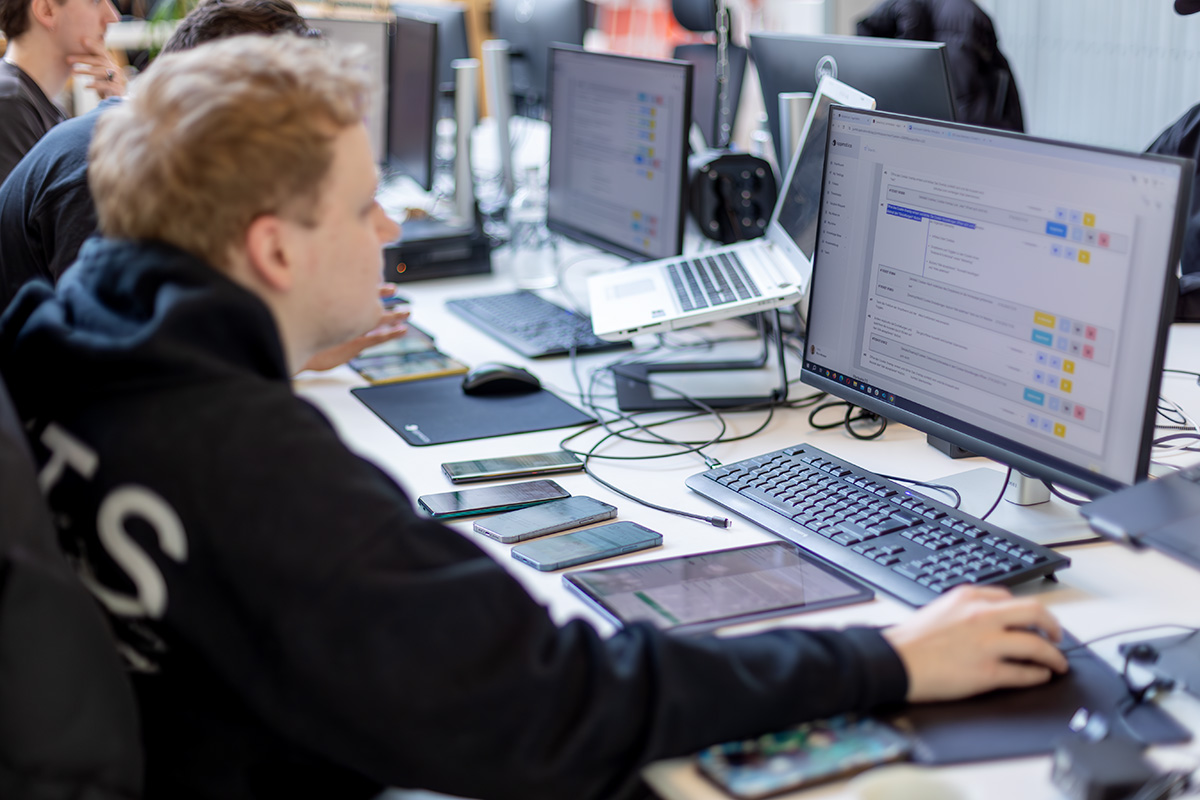 Tester in front of laptop and with several devices on the desk