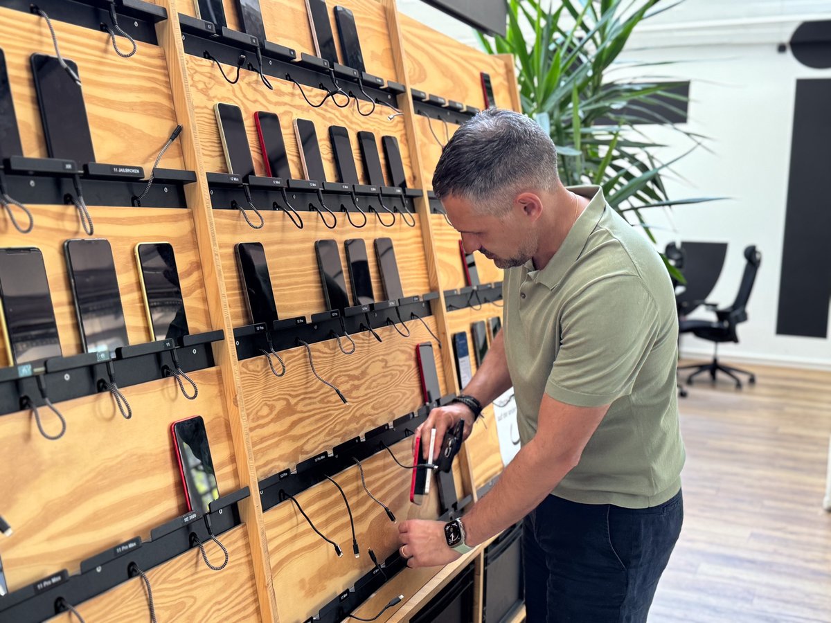 An Appmatics employee stands in front of the Devices Wall and takes a mobile phone from the wall
