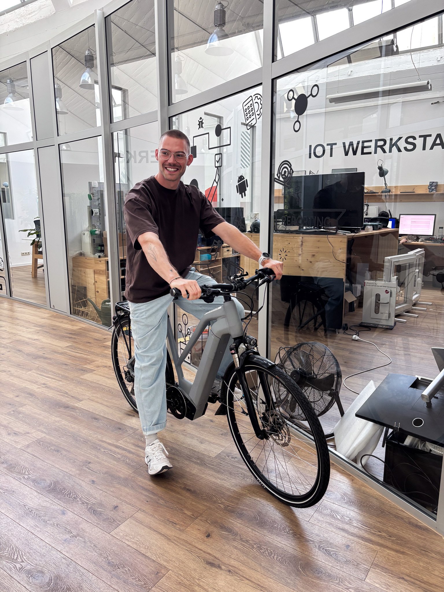 Tester sitzt auf einem E-Bike vor einer IoT-Werkstatt
