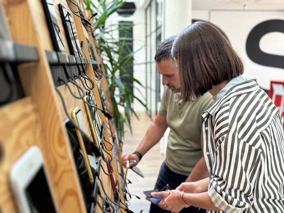 Zwei Appmatics Mitarbeitende stehen vor der Devices Wall und haben Smartphones in der Hand