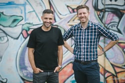 The two CEOs of Appmatics stand in front of a graffiti wall and smile into the camera